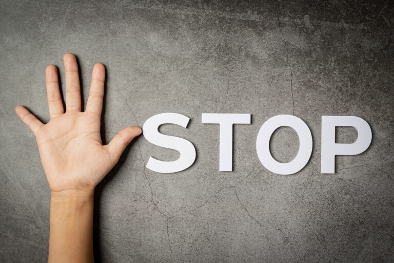 word « stop » with child’s hand on dark background