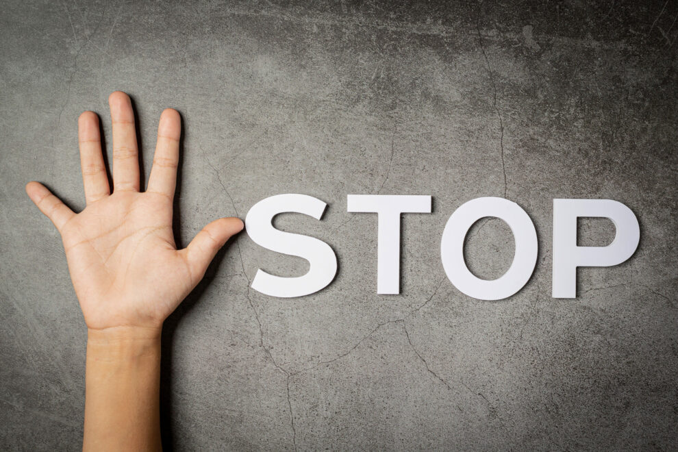 word « stop » with child’s hand on dark background