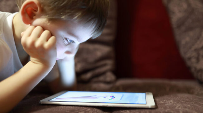 Child with tablet on sofa at home