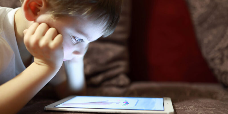 Child with tablet on sofa at home